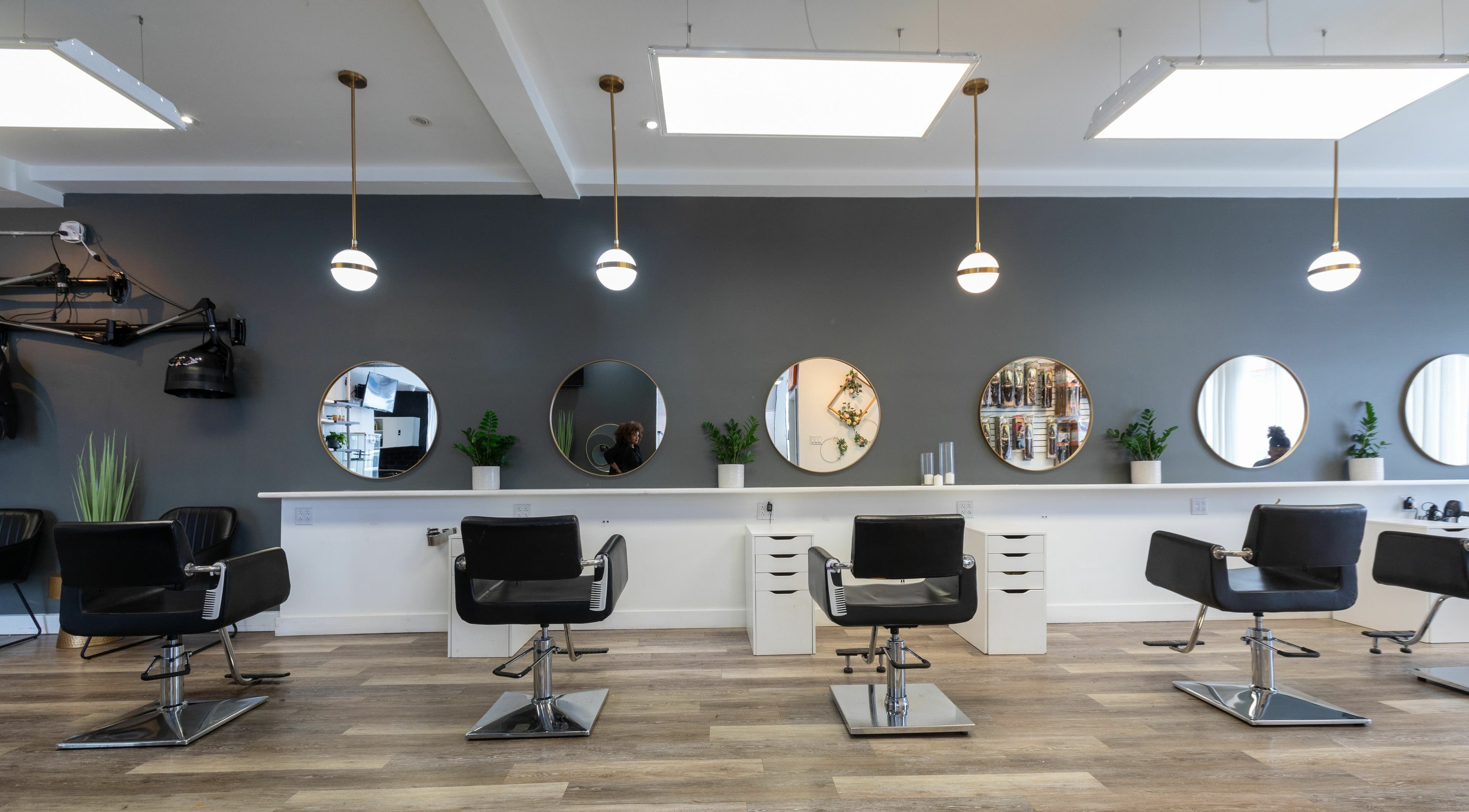 Intérieur moderne du Salon Glam Ô Naturel à Montréal, Québec, CA, avec fauteuils de coiffure élégants et miroirs ronds.
