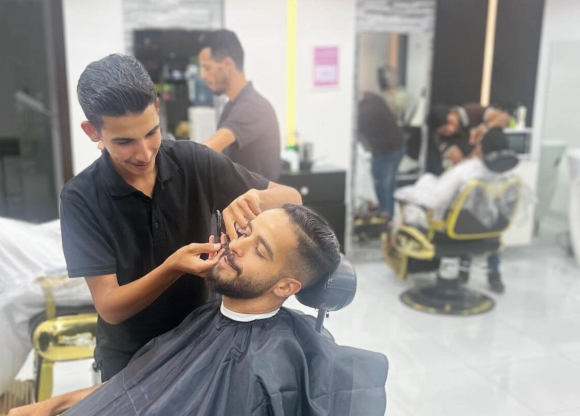 A skilled barber trims a customer's beard at Kenchie Gents Salon - Jumeirah, Dubai, Dubai, AE.