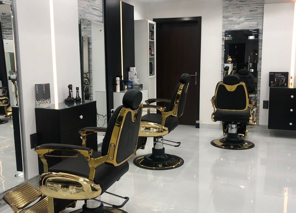 Stylish interior of Kenchie Gents Salon - Jumeirah, Dubai, AE with luxurious golden barber chairs.
