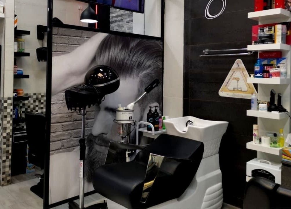 Modern styling station at Kenchie Gents Salon Al Nahda, Dubai, AE, featuring sleek equipment and shelving.