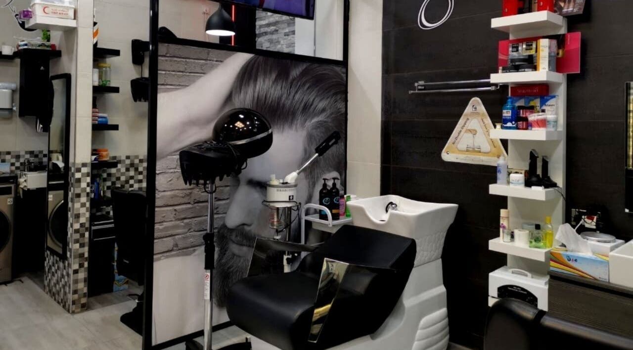 Modern styling station at Kenchie Gents Salon Al Nahda, Dubai, AE, featuring sleek equipment and shelving.