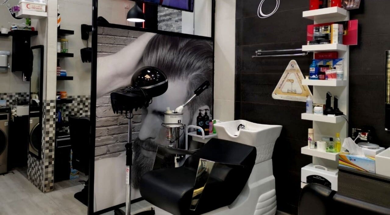 Modern styling station at Kenchie Gents Salon Al Nahda, Dubai, AE, featuring sleek equipment and shelving.
