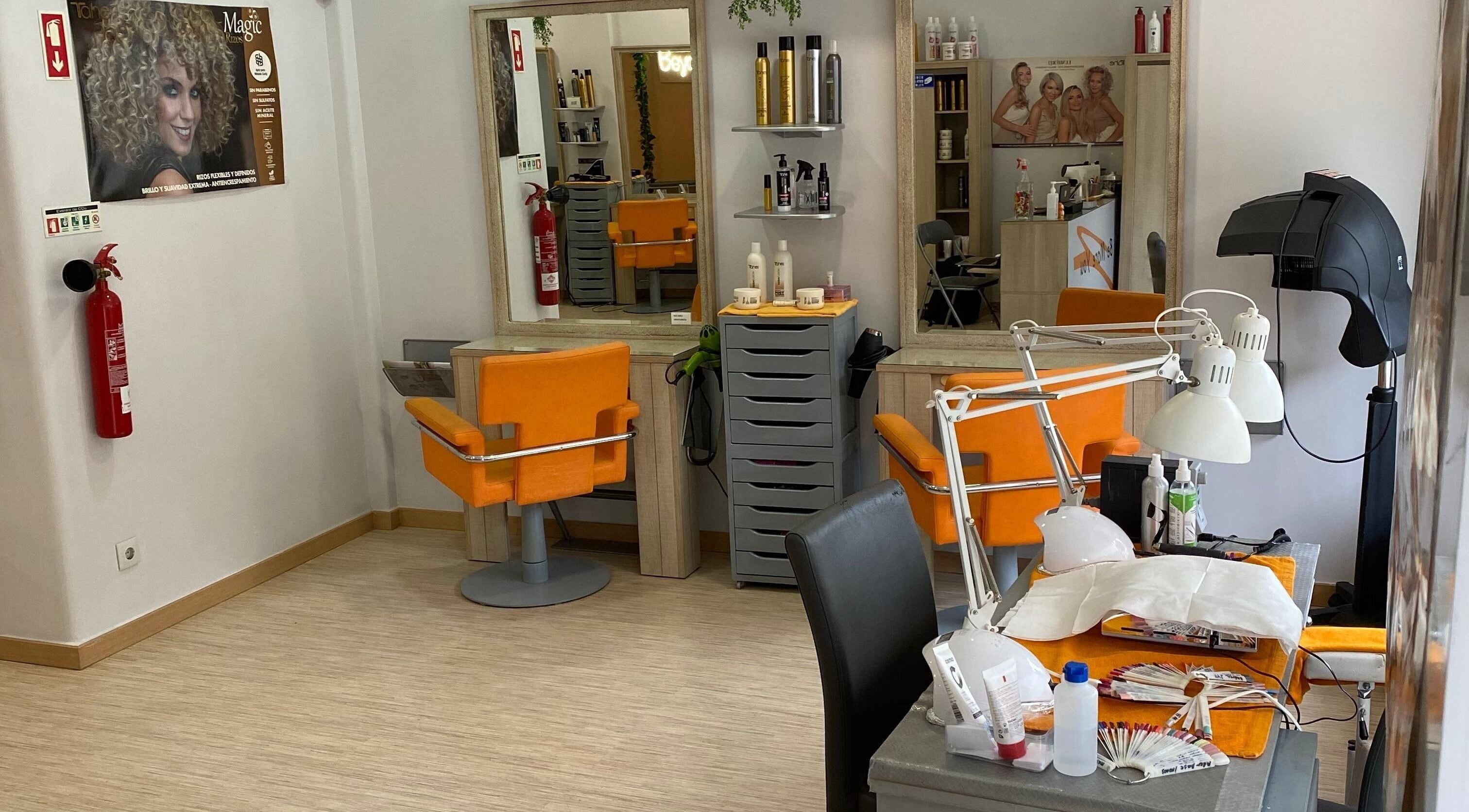 Interior moderno do salão Be More You em Linda-a-Velha, Lisboa, PT, com cadeiras laranja vibrantes.