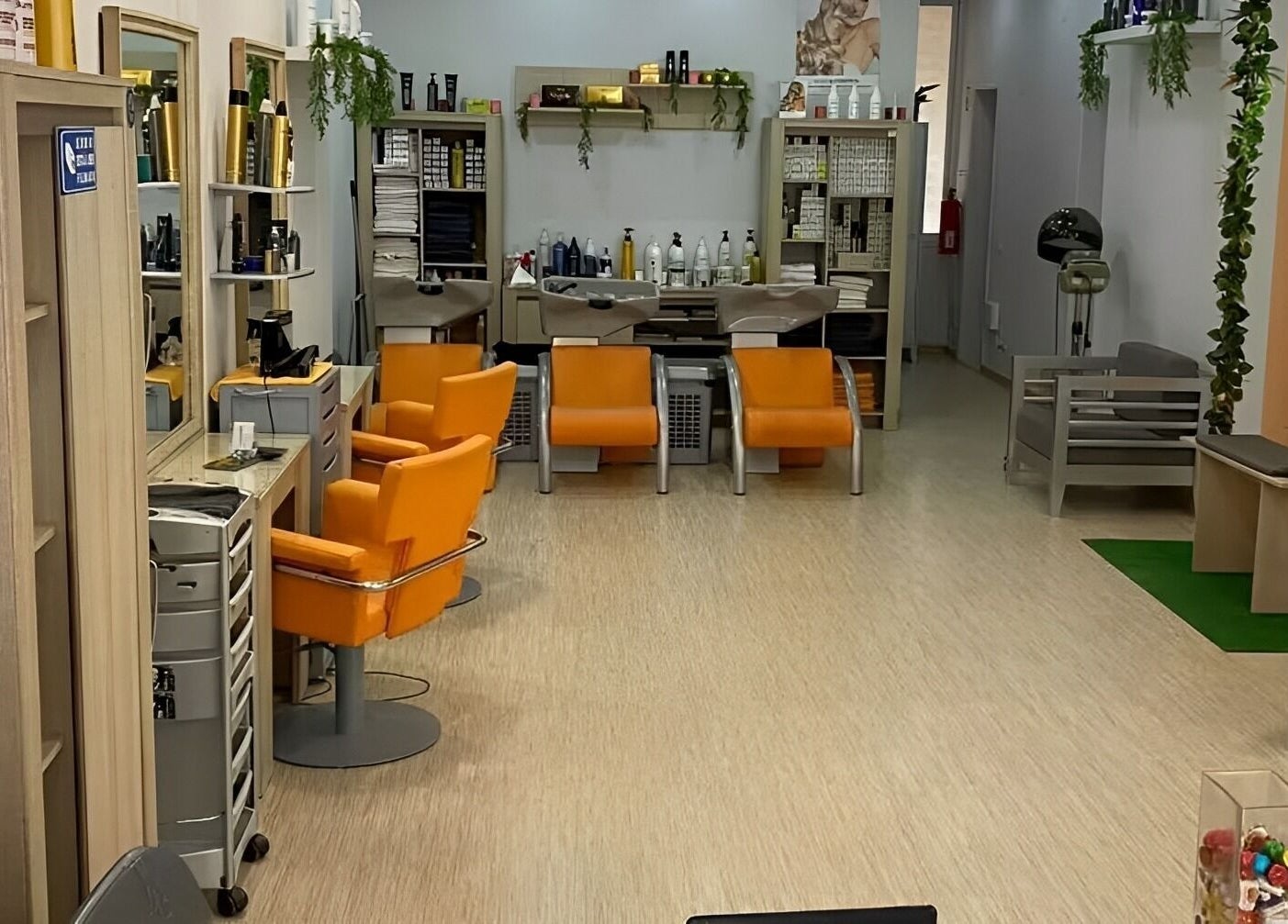 Interior elegante do salão Be More You, Linda-a-Velha, Lisboa, PT, com cadeiras laranja vibrantes.