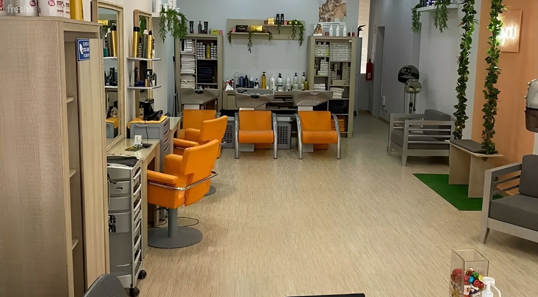 Interior elegante do salão Be More You, Linda-a-Velha, Lisboa, PT, com cadeiras laranja vibrantes.