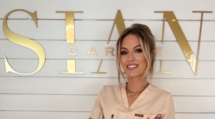 Professional at Sian Carrie Studio smiling in front of the logo in Chelmsford, England, GB.