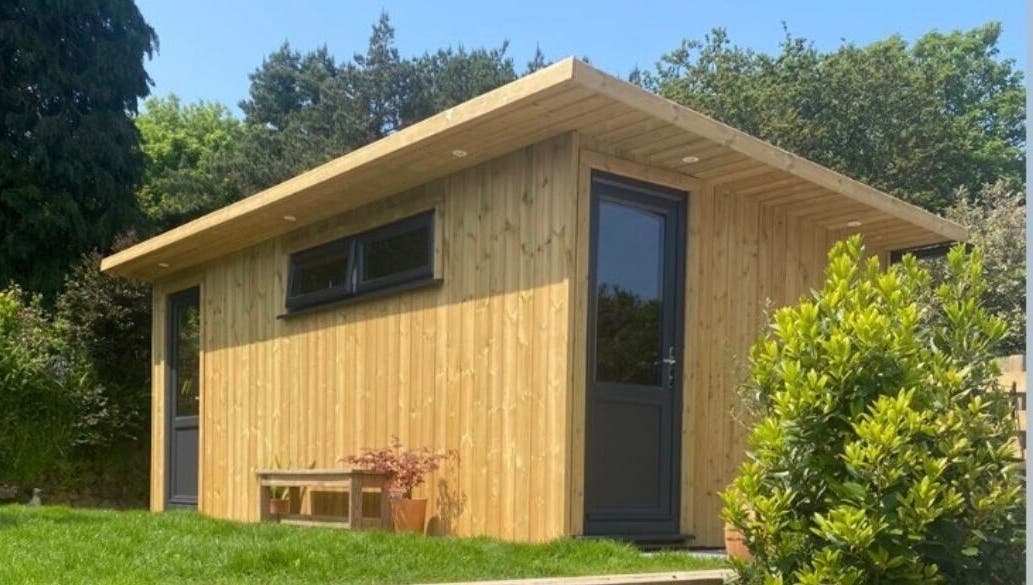 Wooden spa exterior at The LAB by Lisa, Helston, England, GB, surrounded by lush greenery.