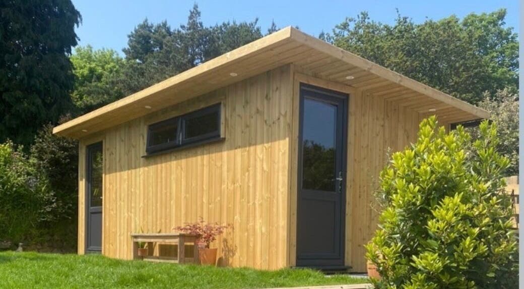 Wooden spa exterior at The LAB by Lisa, Helston, England, GB, surrounded by lush greenery.