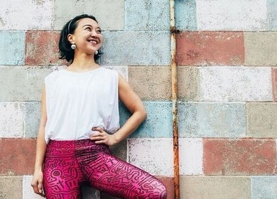 Smiling individual in vibrant attire at Tomoko Pilates NYC, New York, New York, US, against a colorful wall.