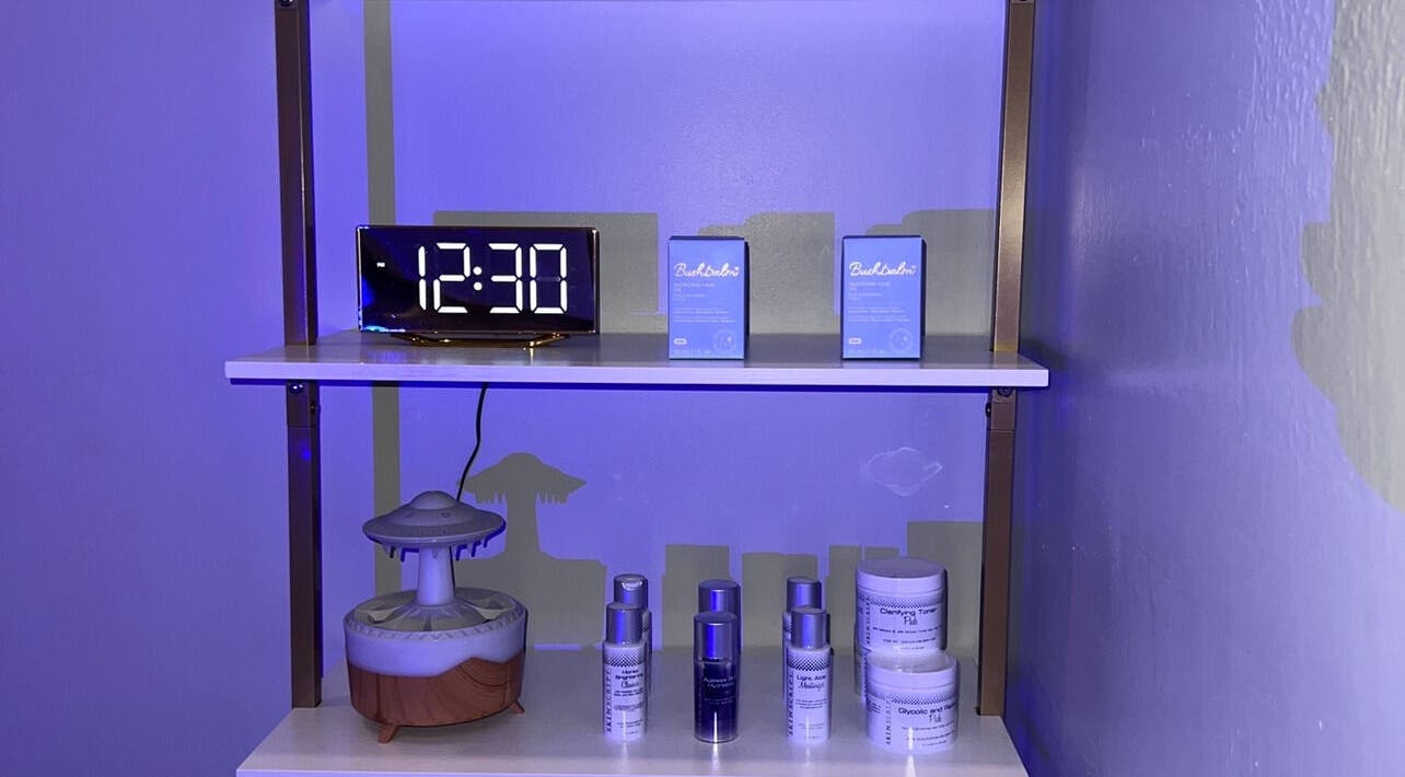 Product display shelf at Elixir Skyn, Nassau, New Providence, BS, featuring a modern digital clock.