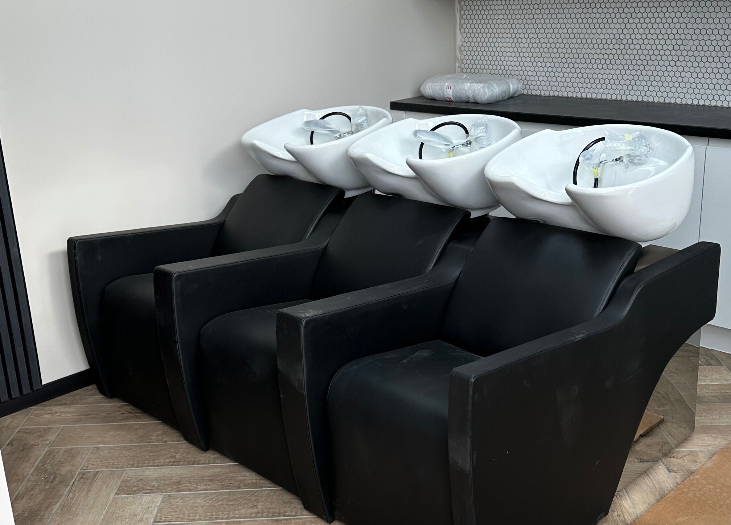 Modern wash stations at Gorgeous Melksham, Melksham, England, GB, featuring sleek black chairs.