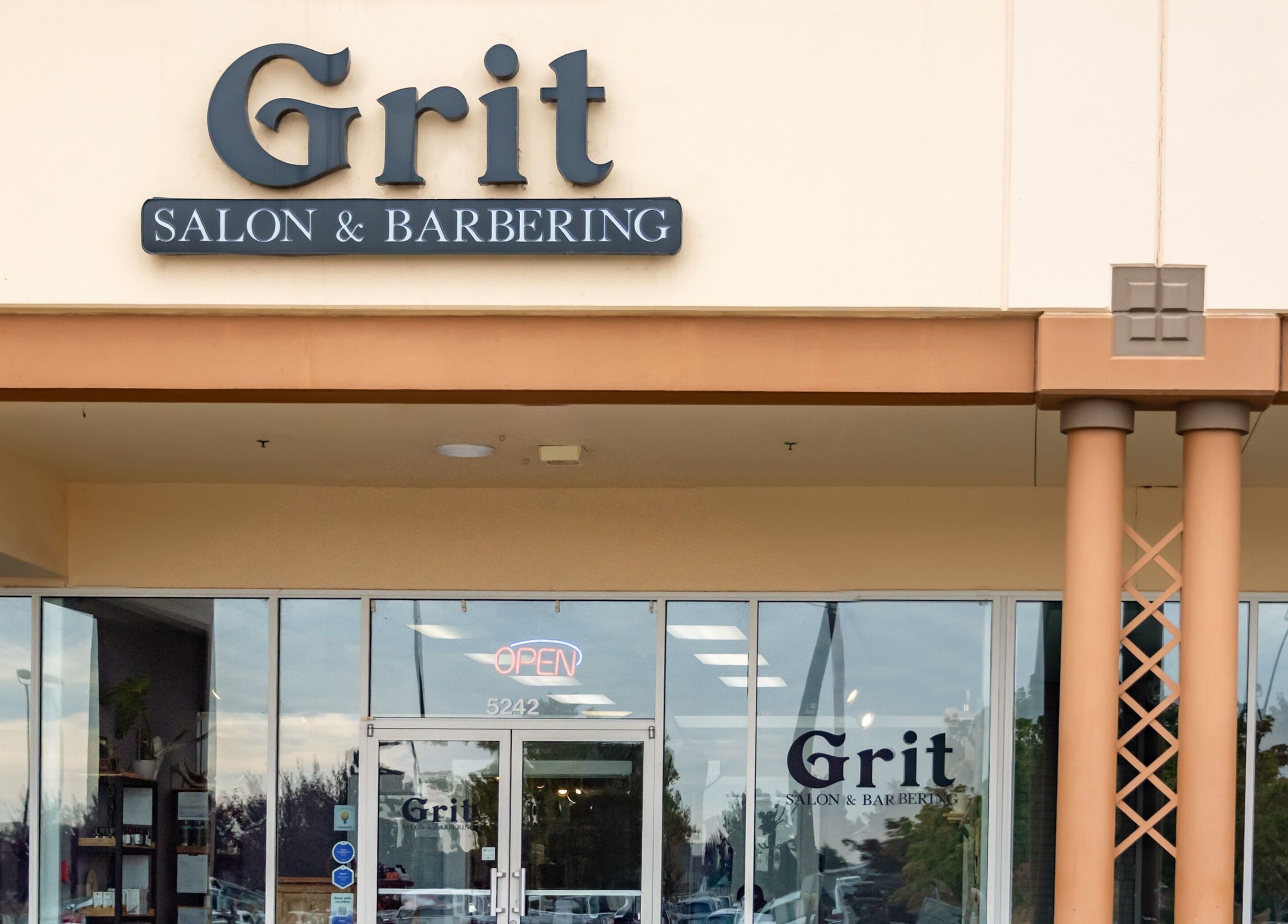 Entrance of Grit Salon & Barbering in Pasco, Washington, US with signage and glass doors.