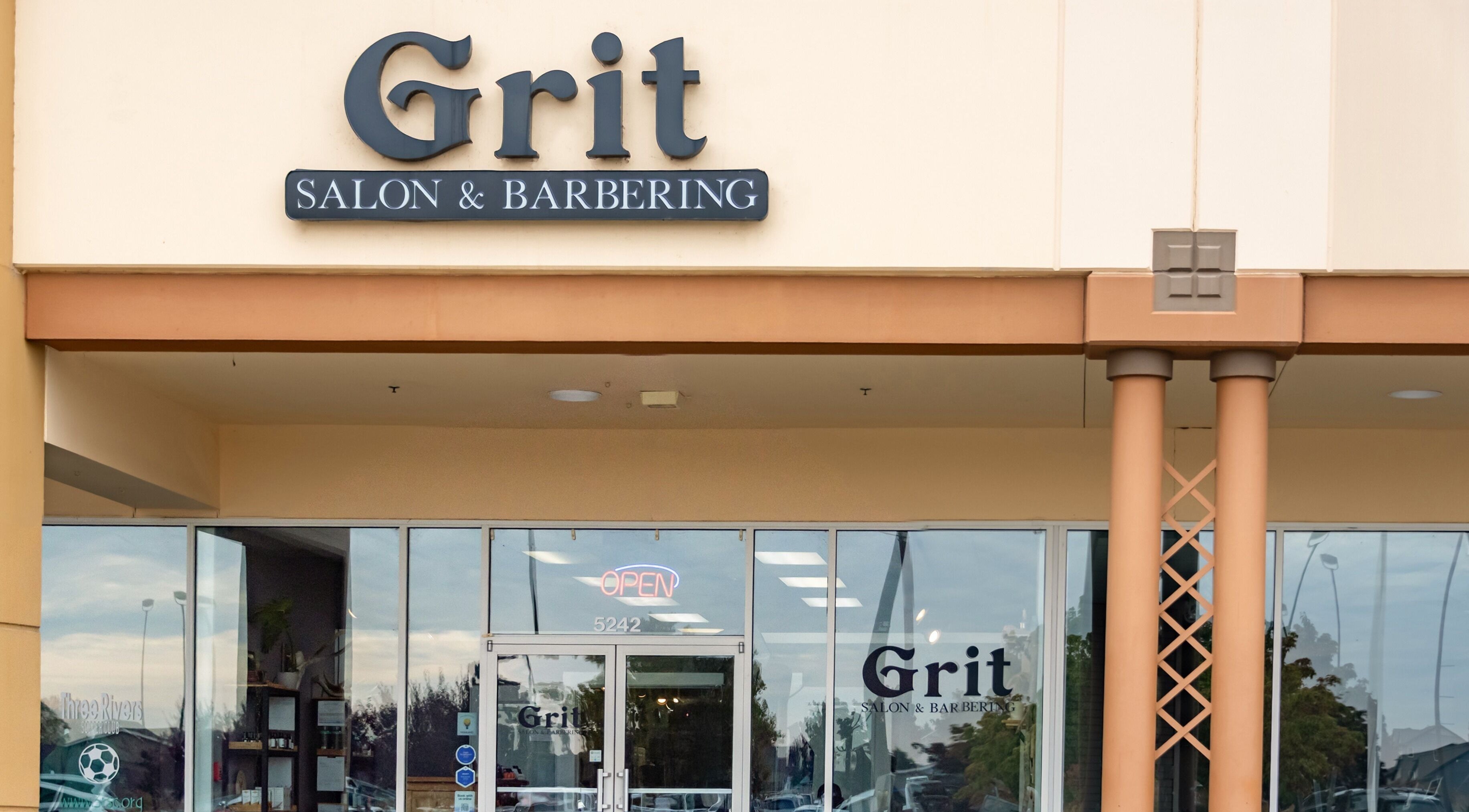 Entrance of Grit Salon & Barbering in Pasco, Washington, US with signage and glass doors.