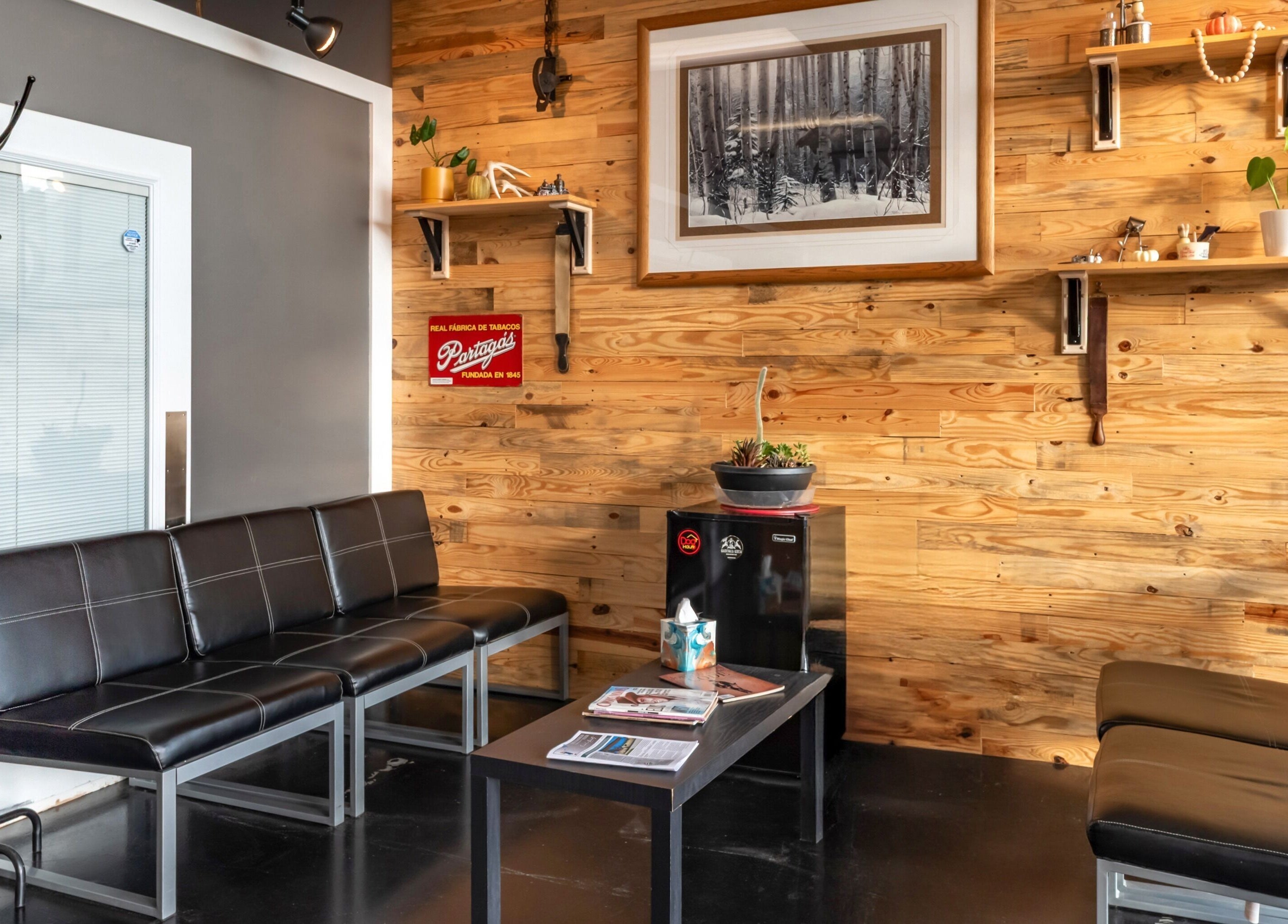Relaxing waiting area at Grit Salon & Barbering, Pasco, Washington, US with stylish black seating and wood accents.