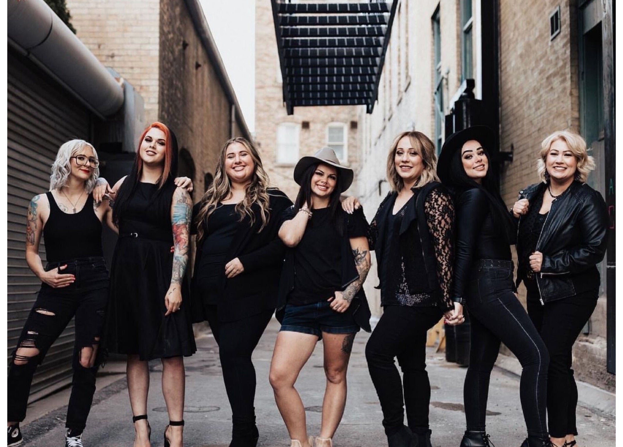 Stylish team at The Beauty Box in Tooele, Utah, US, exudes confidence and camaraderie in a rustic alleyway.