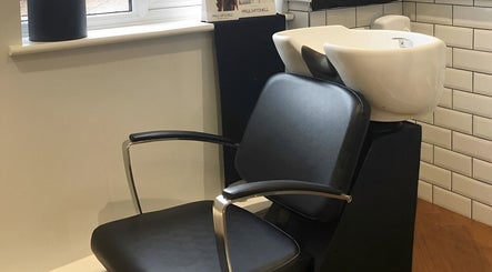 Shampoo station at Salon No.6 Hair And Beauty, Norwich, England, GB, featuring a modern black chair and sink.
