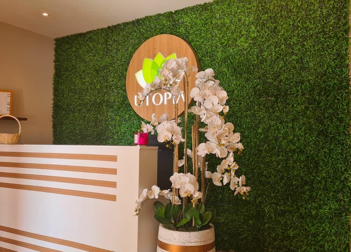 Utopia Spa reception in Dubai, Dubai, AE with lush green wall and elegant orchid decor.