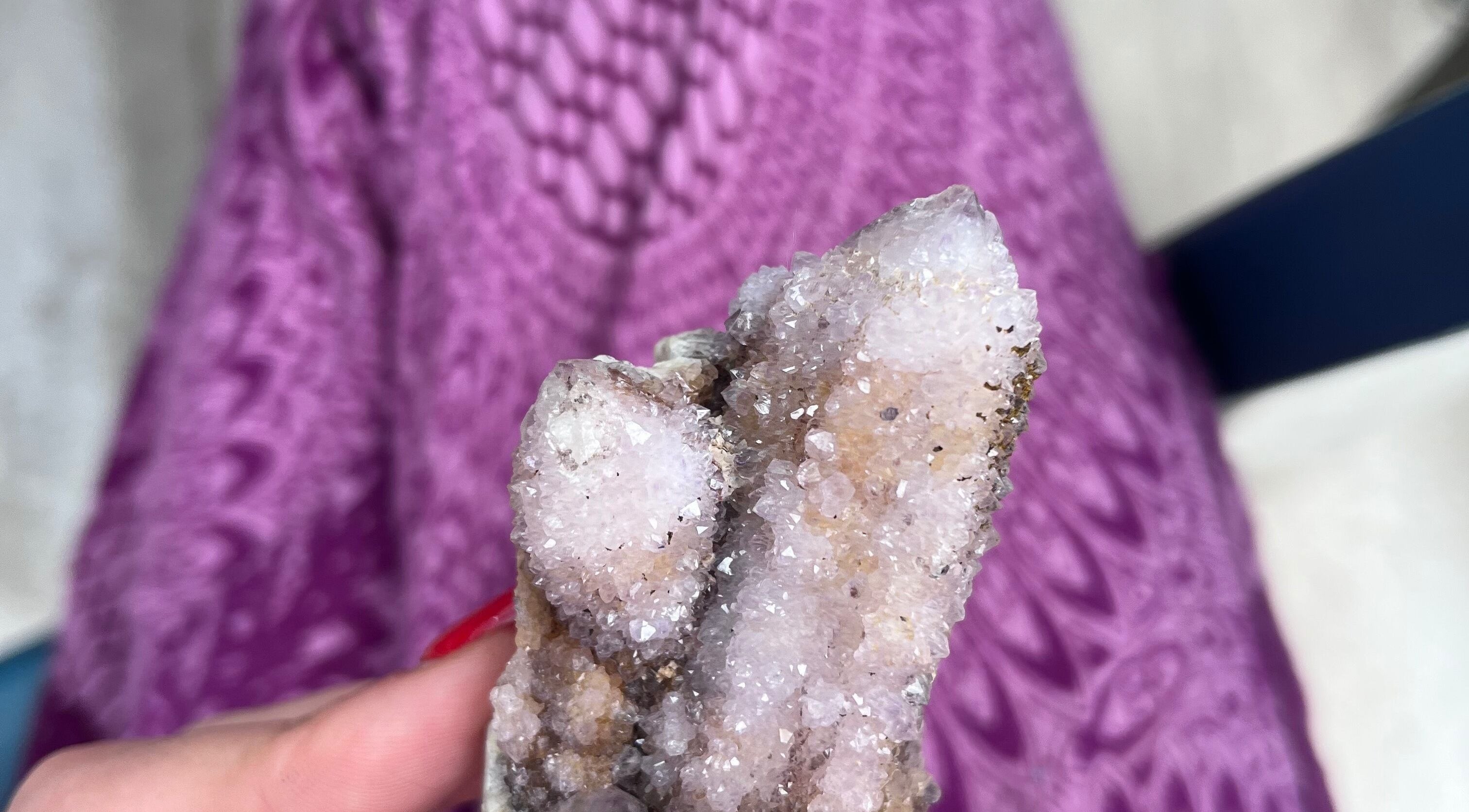 Hand holding sparkling crystal at Shadow Sanctuary Healing, Randburg, Gauteng, ZA. Purple-patterned background.