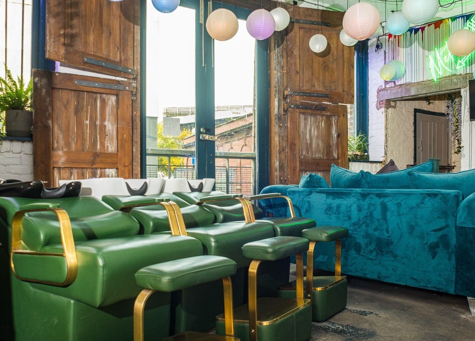 Stylish interior of Metamorph Haus in Liverpool, England with green chairs and teal couch under paper lanterns.