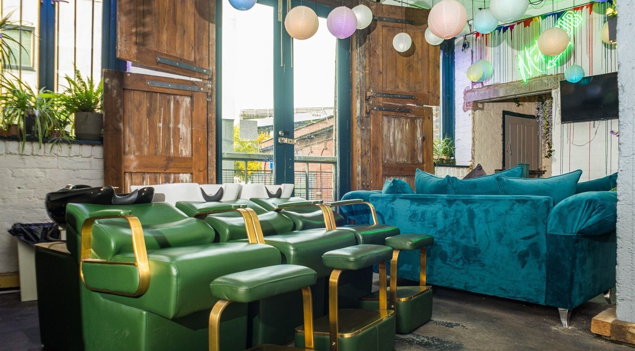 Stylish interior of Metamorph Haus in Liverpool, England with green chairs and teal couch under paper lanterns.