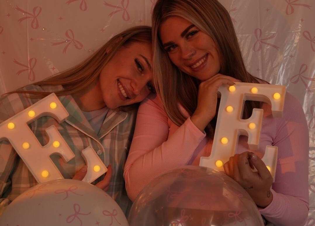 Two smiling women holding lit letters at Evil Eyes Beauty Studio, Roodepoort, Gauteng, ZA.