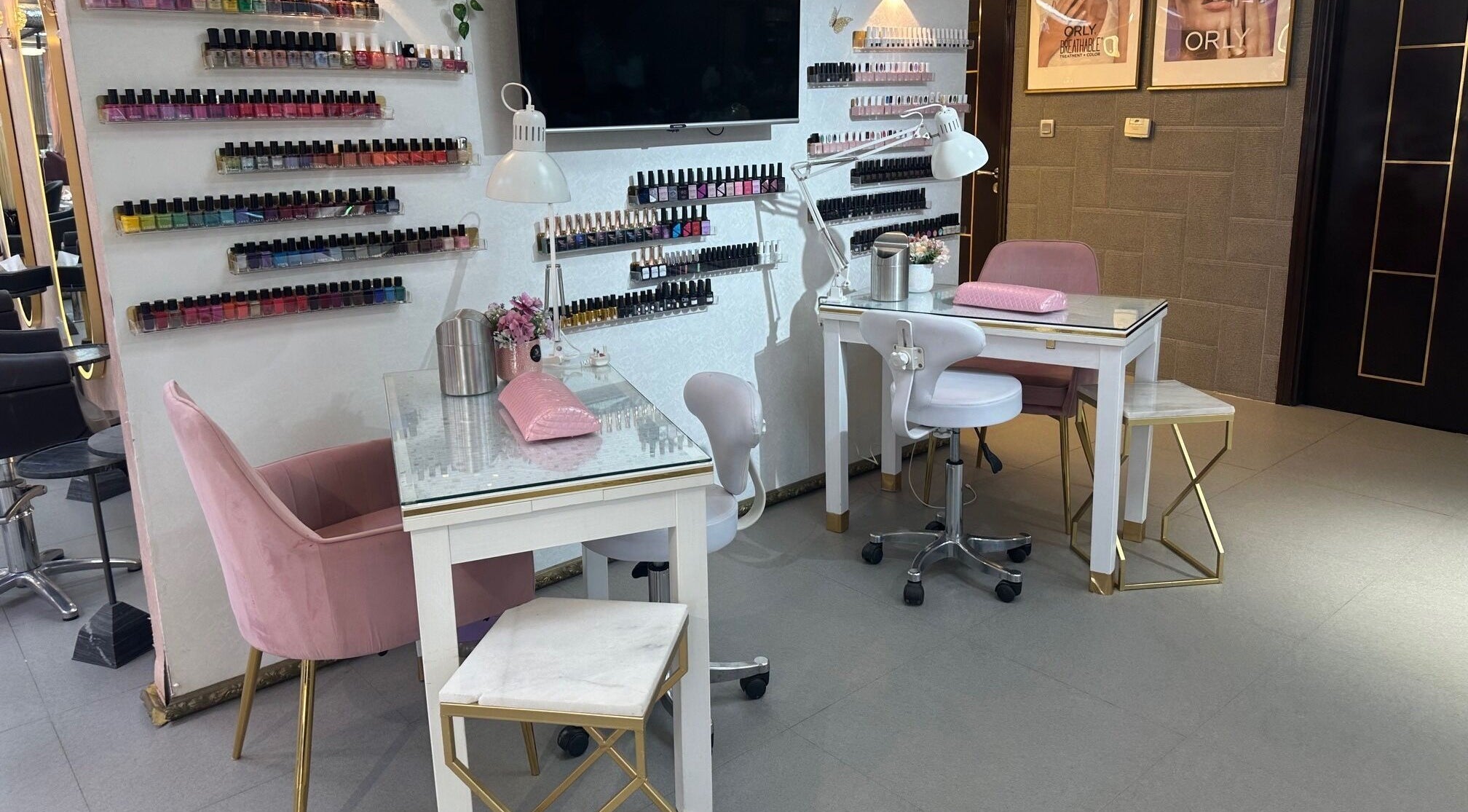 Chic nail studio at Juan Salon, Dubai, AE features elegant chairs, nail polish display, and modern lighting.