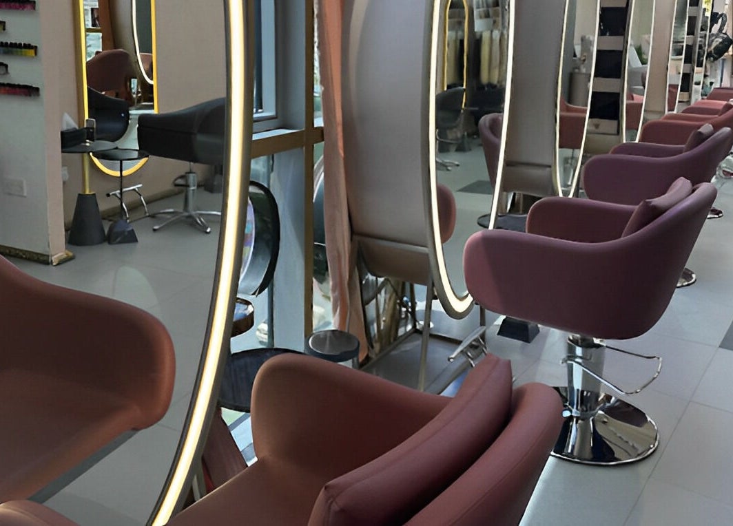 Stylish interior of Juan Salon in Dubai, AE, featuring modern pink salon chairs and illuminated mirrors.