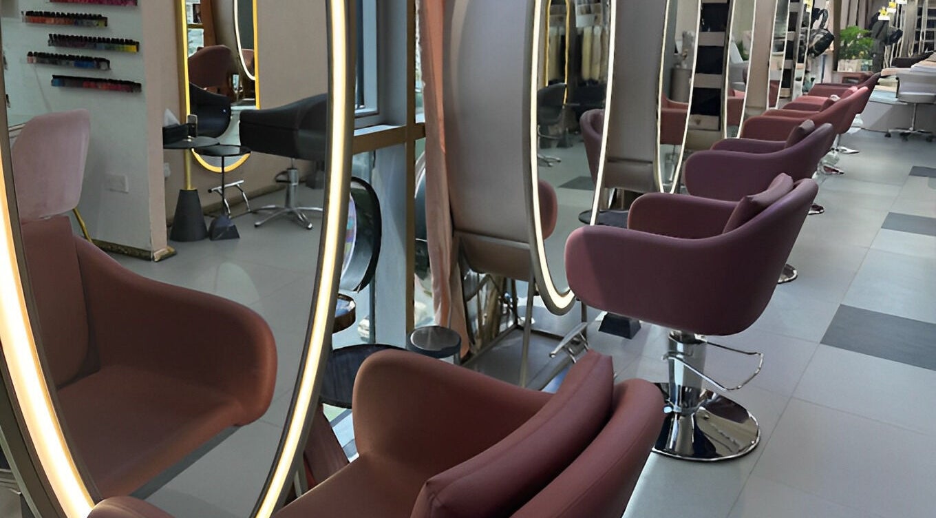 Stylish interior of Juan Salon in Dubai, AE, featuring modern pink salon chairs and illuminated mirrors.