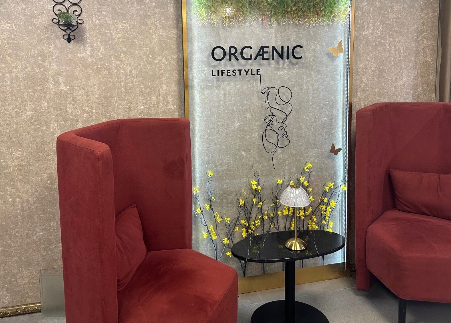 Elegant lounge with red chairs at Juan Salon, Dubai, AE, featuring decorative plants and soft lighting.