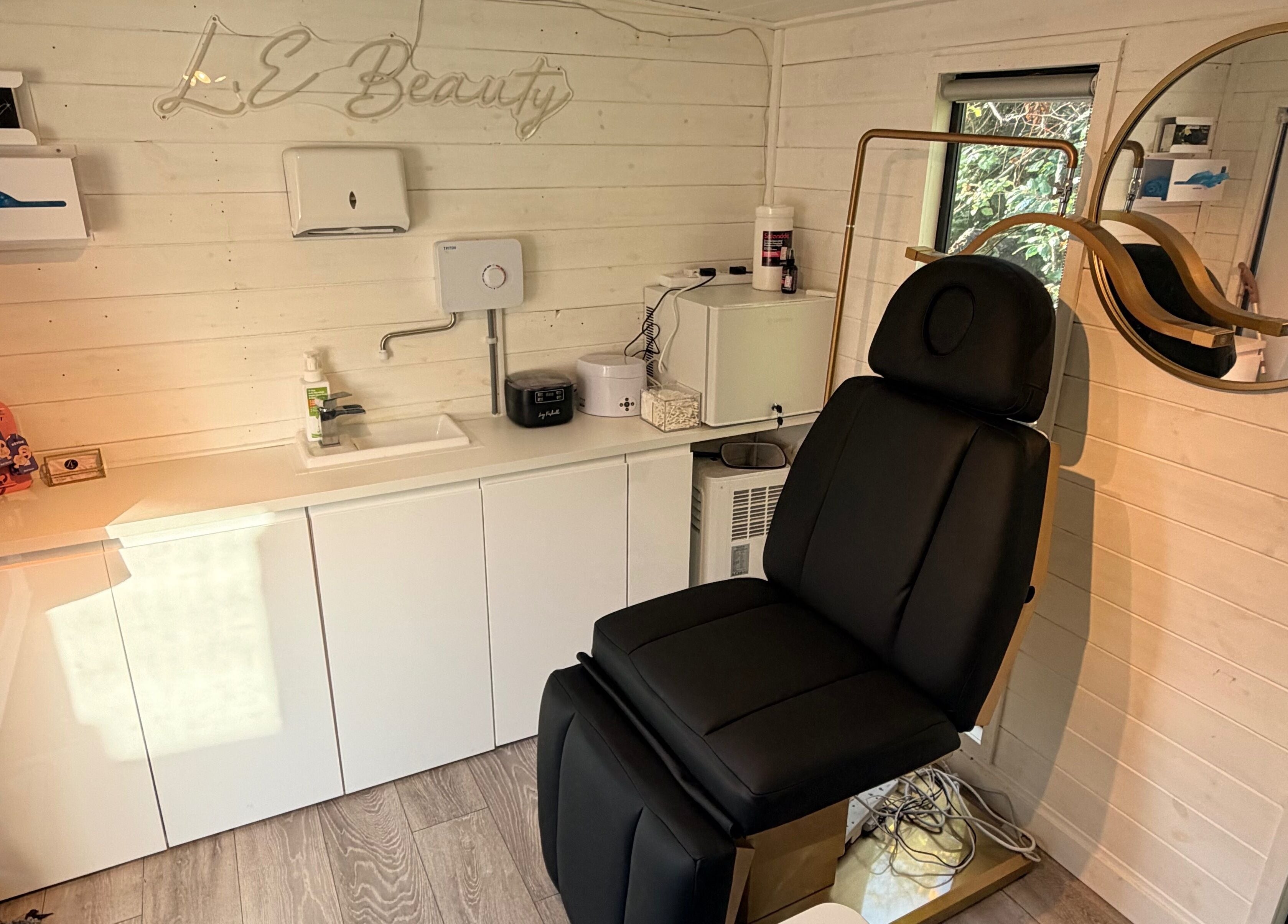 Tranquil treatment room at L.E Beauty and Aesthetics, Rowlands Castle, England, with a sleek black chair.