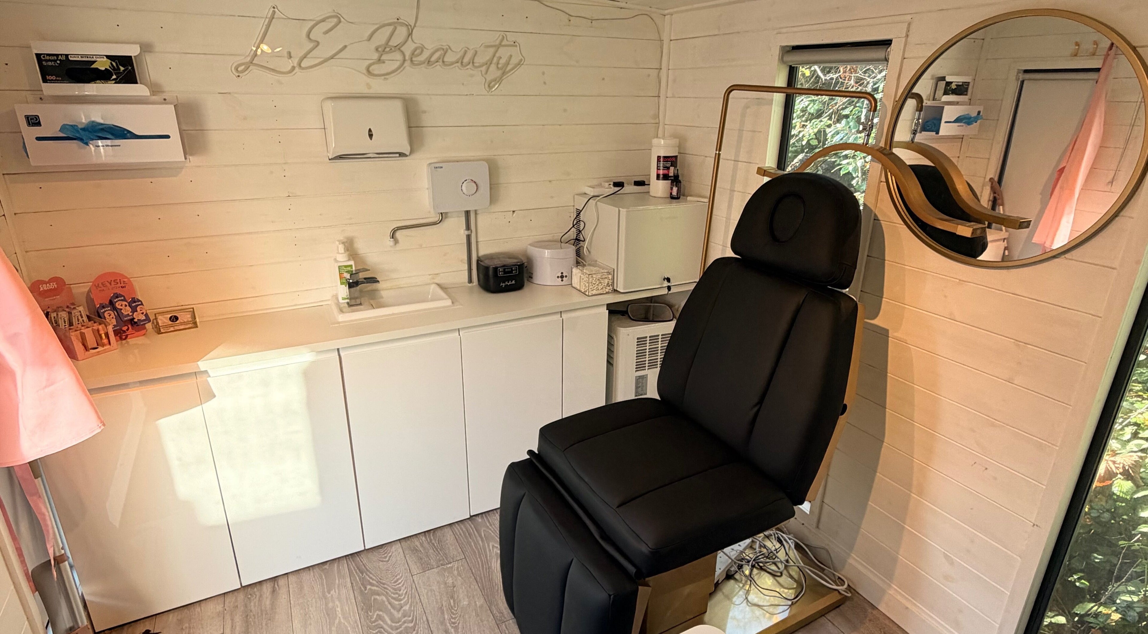 Tranquil treatment room at L.E Beauty and Aesthetics, Rowlands Castle, England, with a sleek black chair.