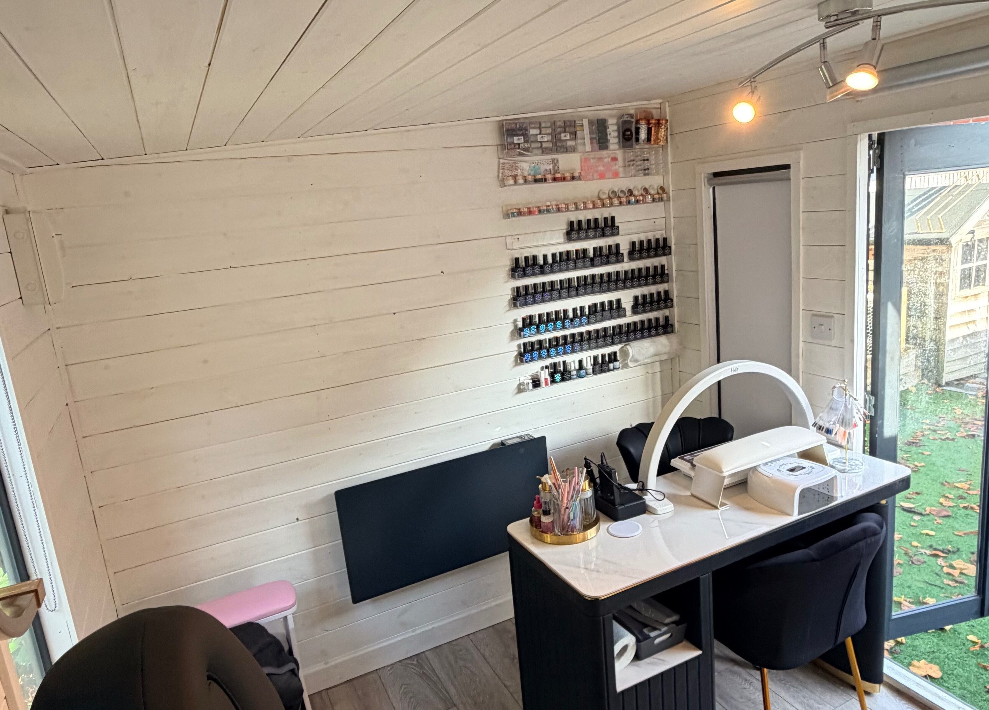 Cozy interior of L.E Beauty and Aesthetics, Rowlands Castle, England, GB with nail polish display and workstations.