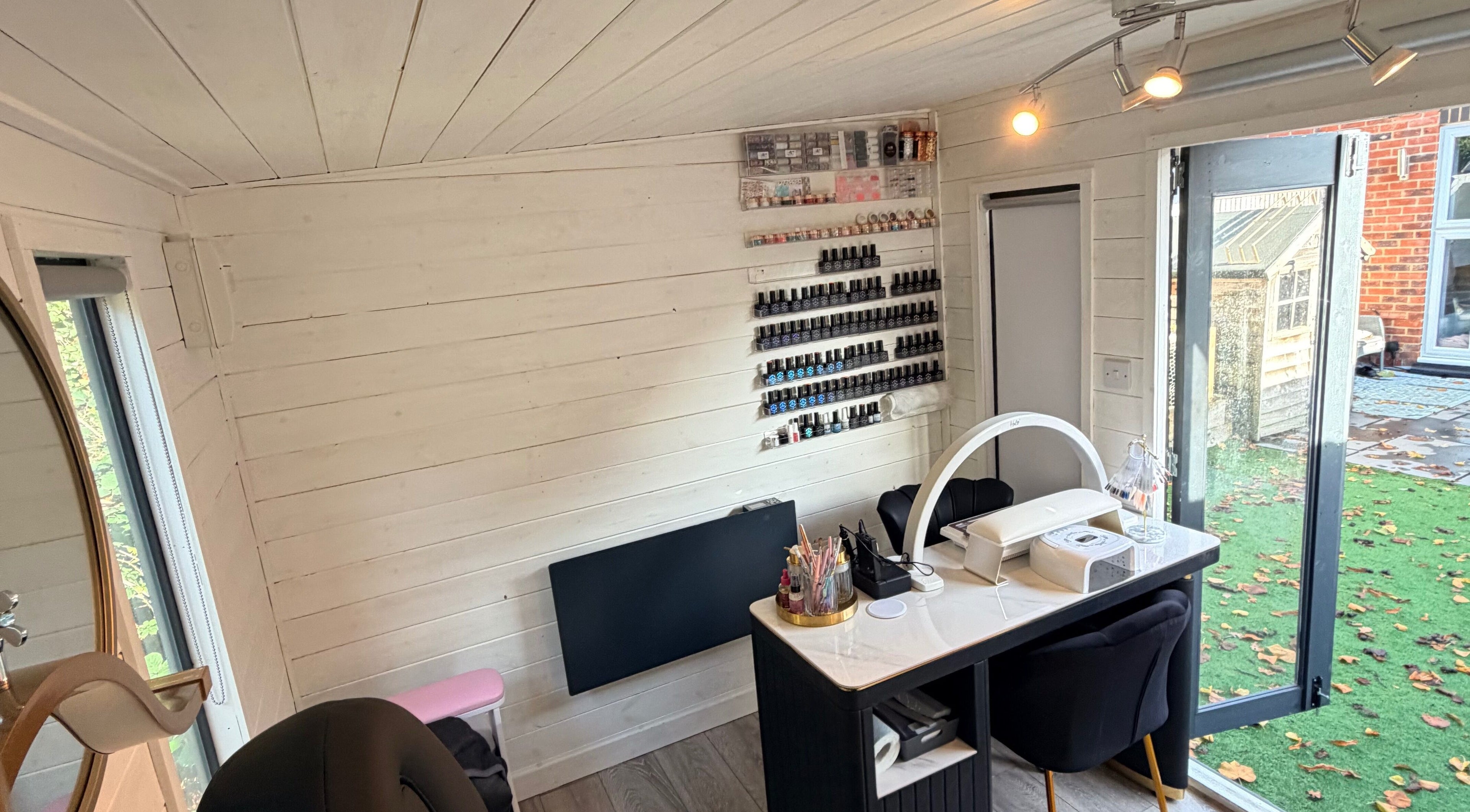 Cozy interior of L.E Beauty and Aesthetics, Rowlands Castle, England, GB with nail polish display and workstations.