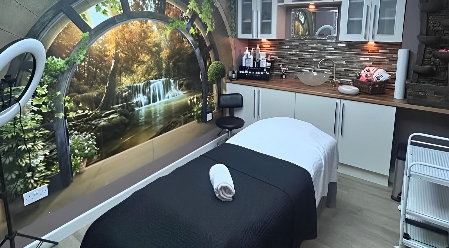 Tranquil spa room at Leila’s Beauty Lounge, Birmingham, England, GB, featuring a waterfall mural and treatment bed.