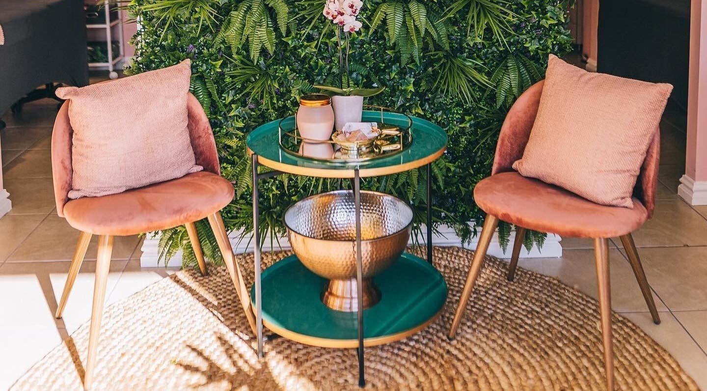 Comfortable seating area at Lola’s Lash Artistry, Westville, KwaZulu-Natal, ZA, with green plants and soft pink chairs.