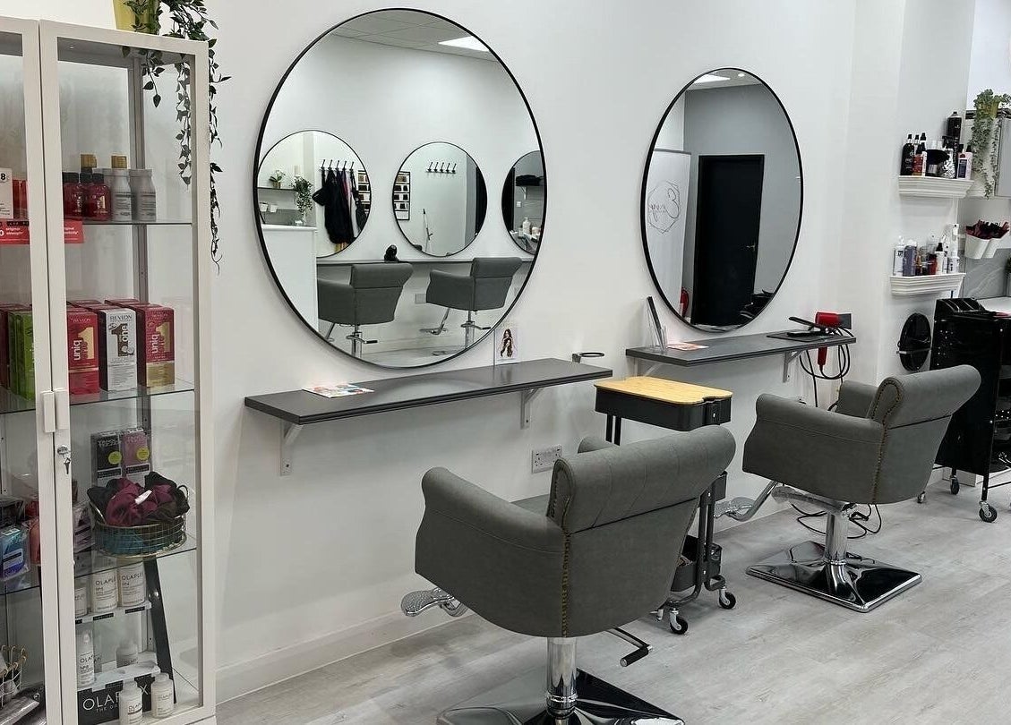 Modern styling chairs at Envy Hair & Extensions, Eastbourne, England, GB salon with sleek decor and products displayed.