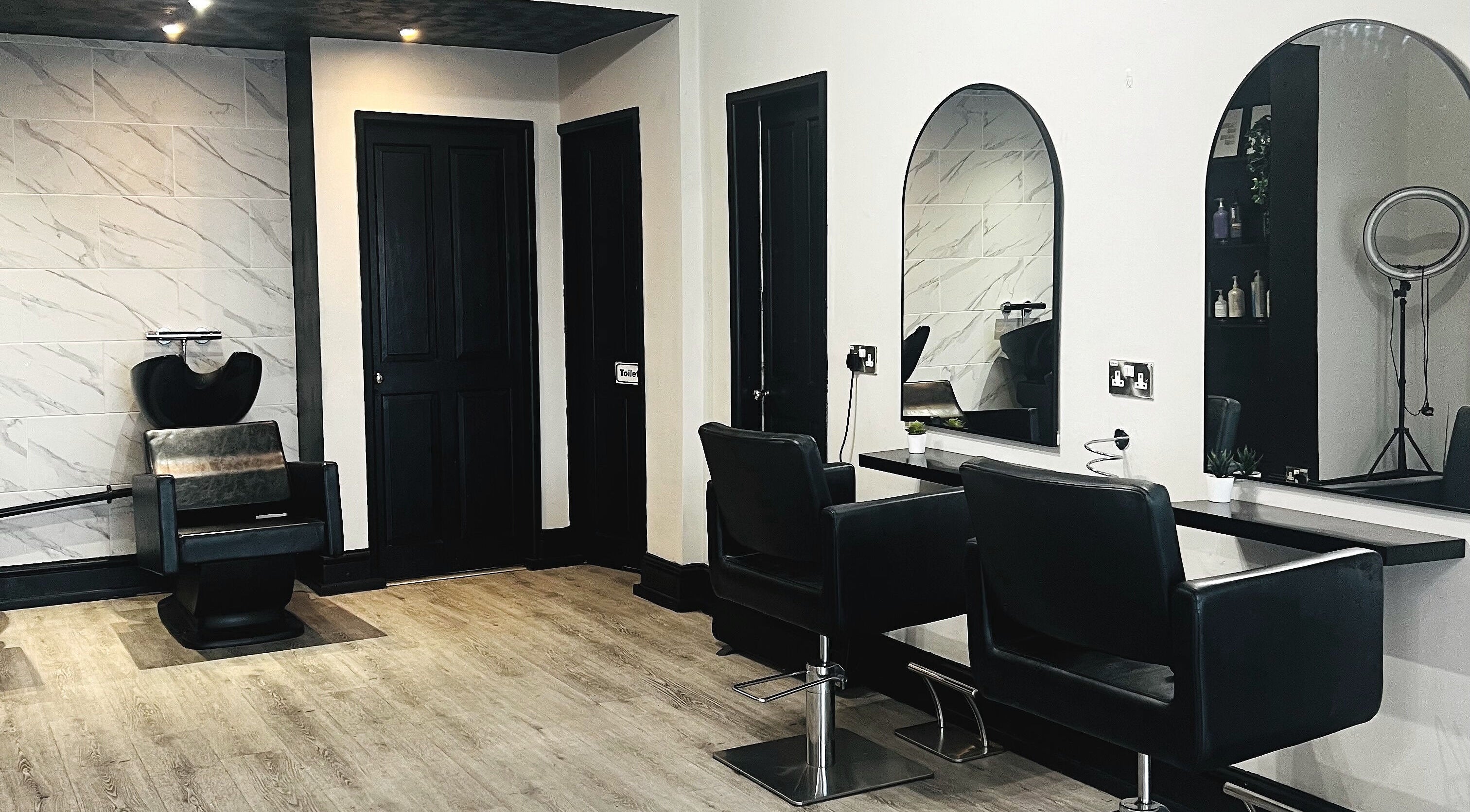 Modern salon interior at Lucia Hair, Lostock Hall, England, GB, featuring sleek chairs and mirrors.