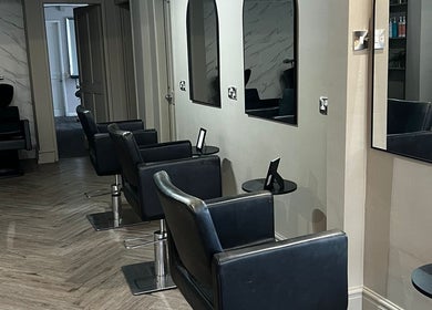 Modern salon seating area at Lucia Hair, Lostock Hall, England, GB, featuring sleek black styling chairs.