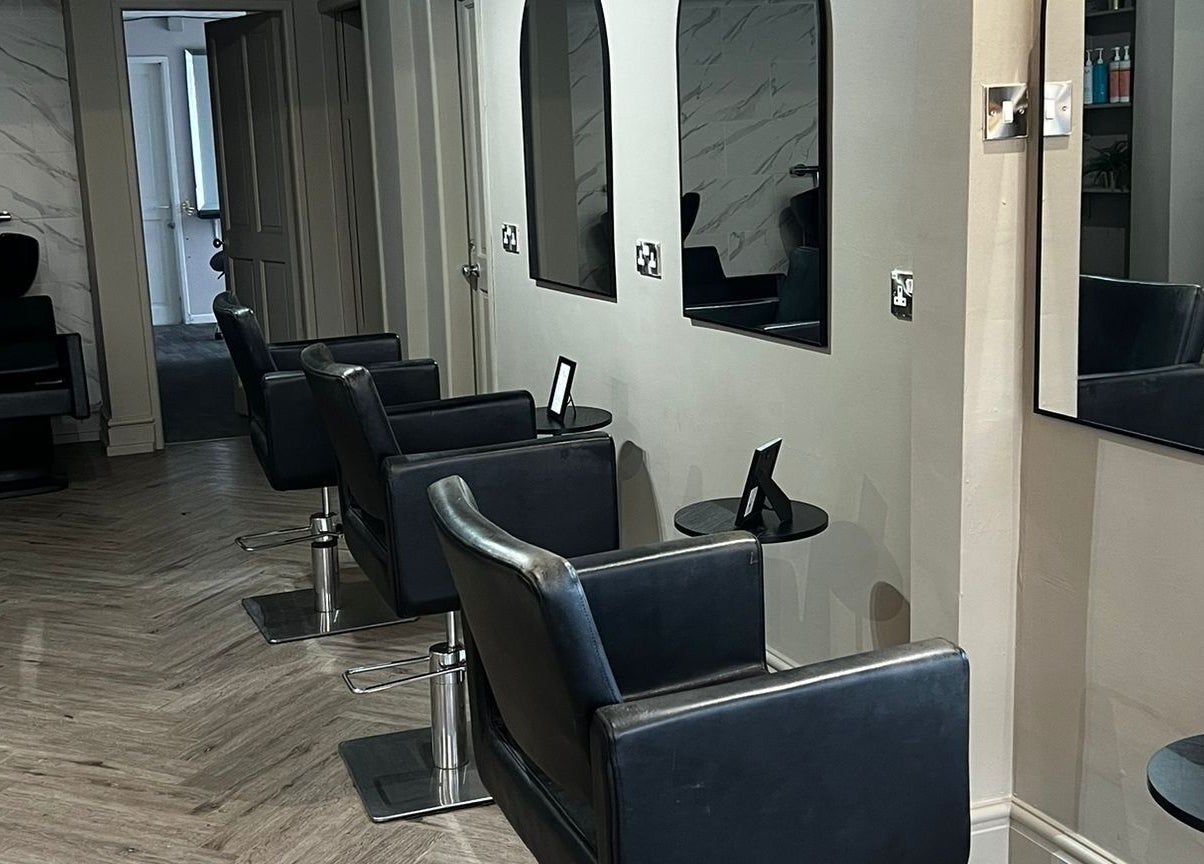 Modern salon seating area at Lucia Hair, Lostock Hall, England, GB, featuring sleek black styling chairs.
