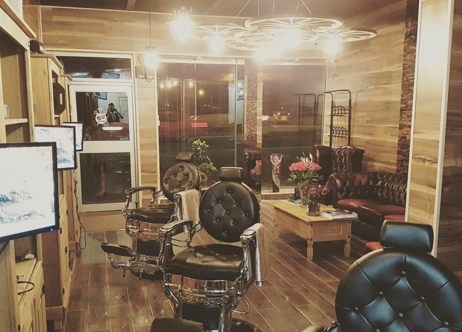 Warm interior of Sharp Scissors salon in Glasgow, Scotland, GB featuring leather chairs and wood decor.