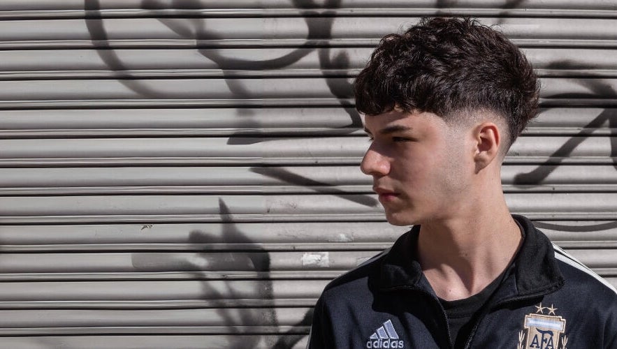 Joven con corte de cabello moderno frente a un fondo urbano en BH Estudio, Piñeyro, Provincia De Buenos Aires, AR.