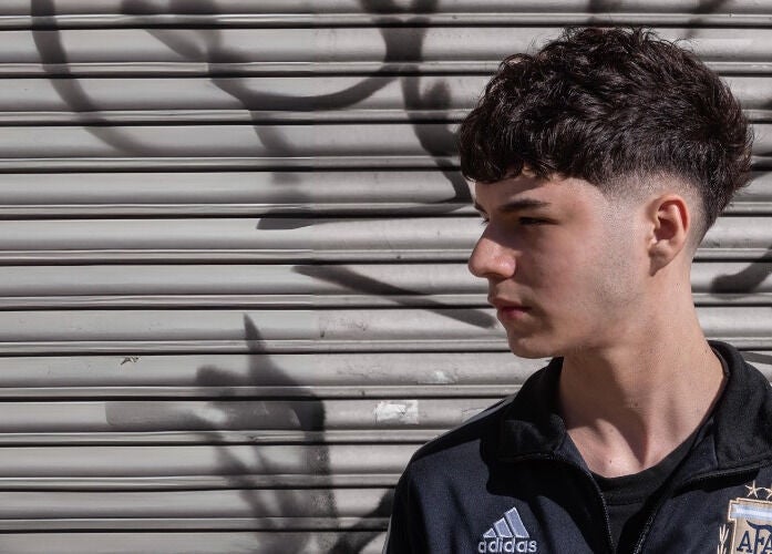 Joven con corte de cabello moderno frente a un fondo urbano en BH Estudio, Piñeyro, Provincia De Buenos Aires, AR.