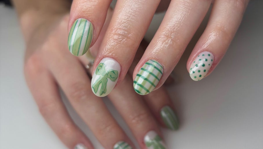 Stylish green nail art at The Nail Garden, Lansing, Michigan, US. Perfect blend of stripes, dots, and bow designs.