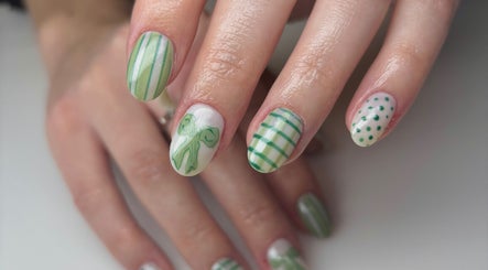 Stylish green nail art at The Nail Garden, Lansing, Michigan, US. Perfect blend of stripes, dots, and bow designs.
