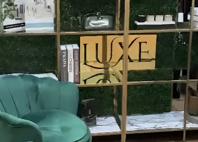 Elegant green chair beside decor with Luxe Beauty Bar Sydney logo, Earlwood, New South Wales, AU.