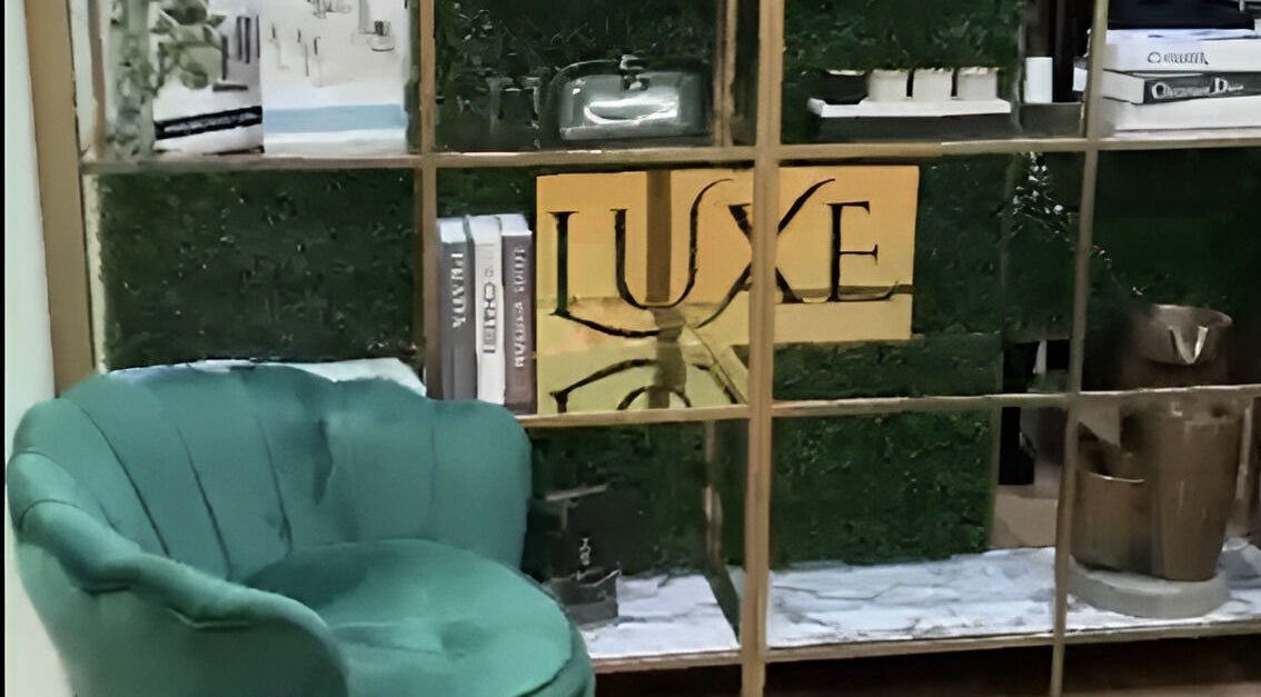 Elegant green chair beside decor with Luxe Beauty Bar Sydney logo, Earlwood, New South Wales, AU.