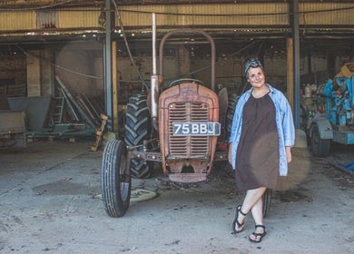 Woman by vintage tractor at HIVEhair by Tabbie in The Barn, Wrentham, England, GB.