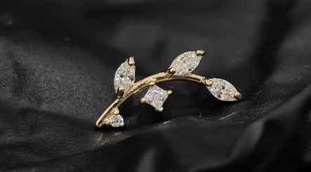 Elegant leaf-shaped gold earring with crystals at Empress Piercing Cardiff, located in Cardiff, Wales, GB.