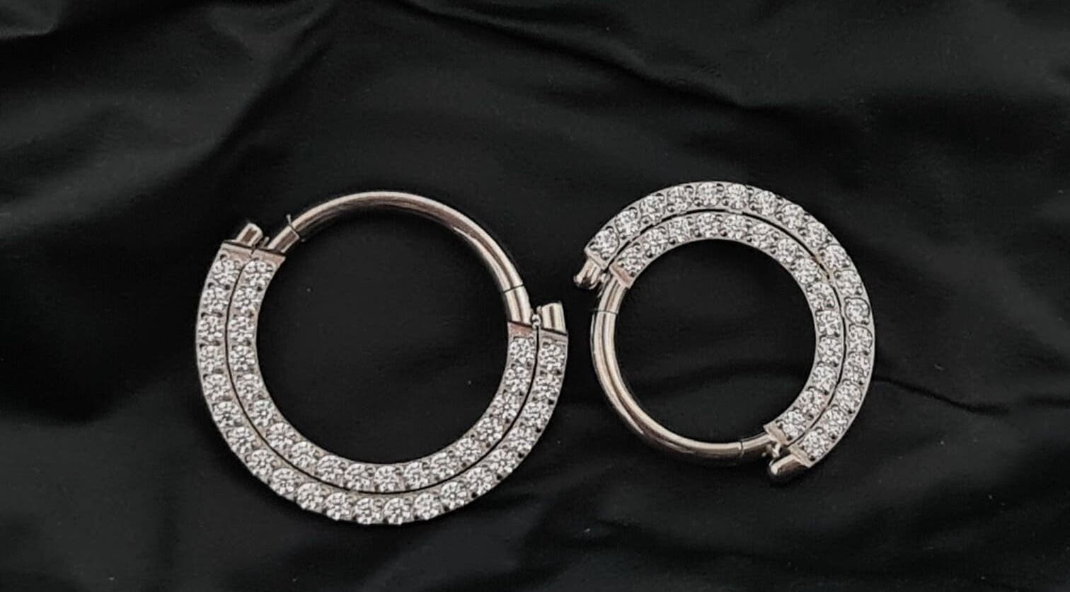 Elegant diamond hoop earrings at Empress Piercing Cardiff, Cardiff, Wales, GB, elegantly displayed on black fabric.