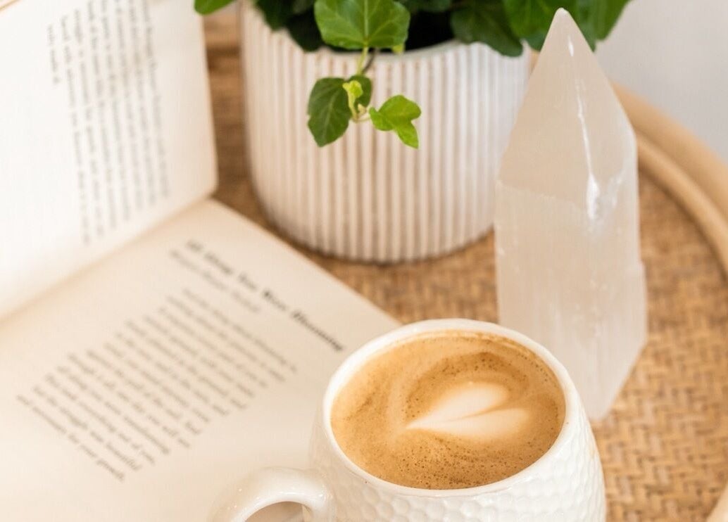 Cozy setting at FMN Studio, Mungret Village, County Limerick, IE with coffee, open book, plant, and crystal.